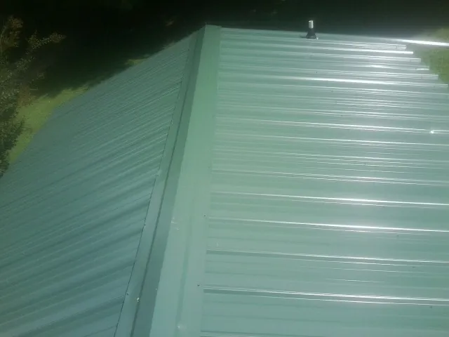 New green metal panels meeting at the ridge of a roof — Flat Roof Repair work by our crew in Thomson