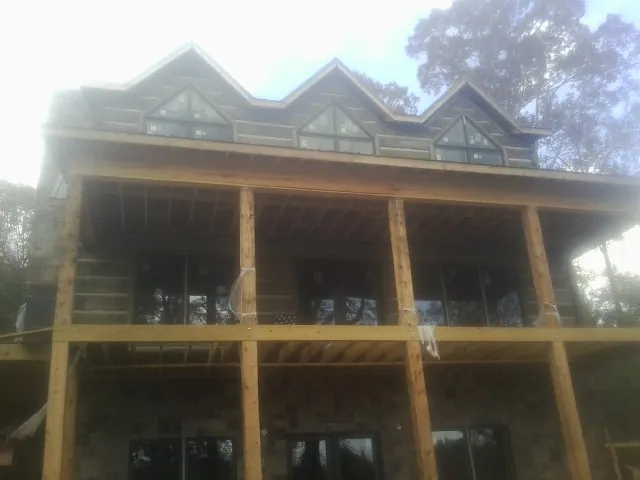 Dormers and porch framing on a large log home under construction — Roof Coating work by our crew in Thomson