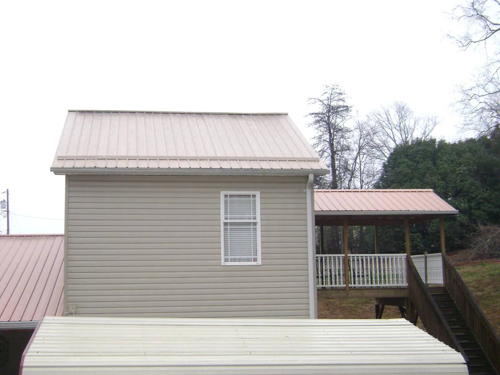 Tan metal roofs on a two story addition and attached porch, from a Roof Replacement job in Thomson