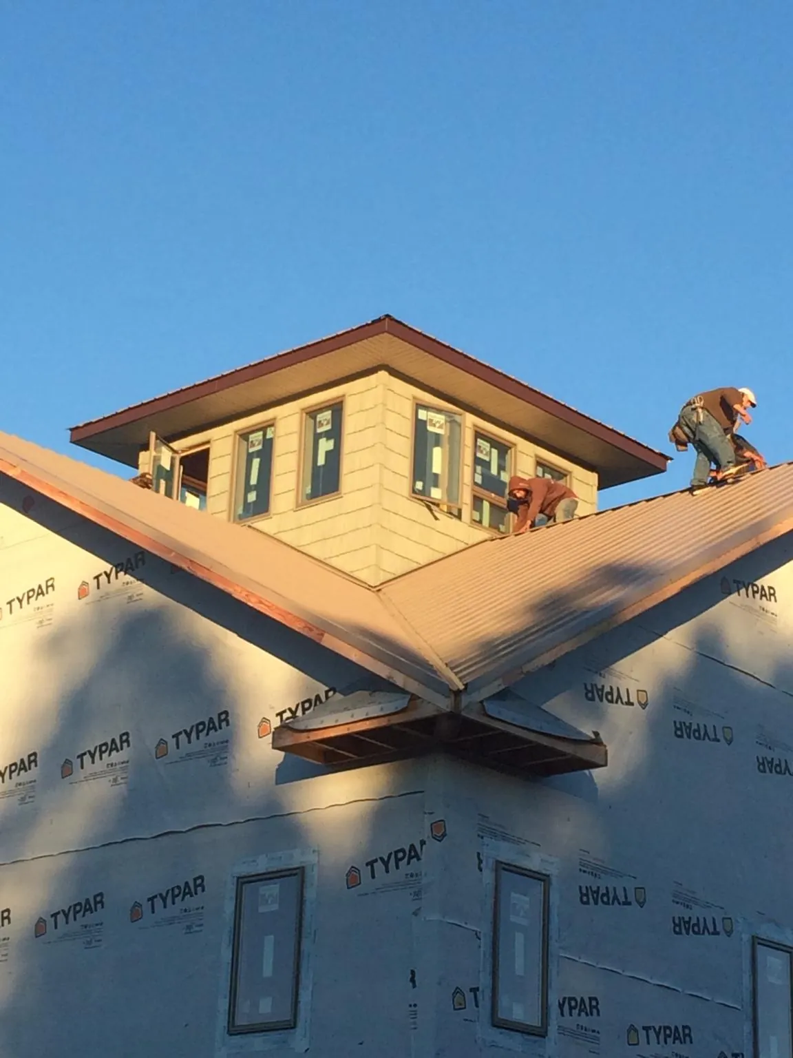 Roofers working around a rooftop cupola on a new metal roof at sunset — Roof Waterproofing in Thomson by Roofing Brothers